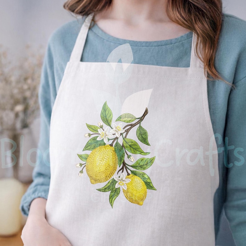 Puede incluir: Delantal blanco con un dise&ntilde;o de rama de lim&oacute;n con limones amarillos, hojas verdes y flores blancas. El delantal est&aacute; hecho de una tela de color claro y tiene un dise&ntilde;o simple y cl&aacute;sico. El delantal lo lleva una persona.