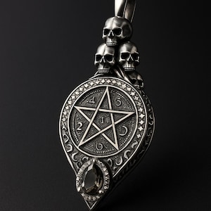 Puede incluir: Colgante plateado con un diseño de pentagrama numerado del 1 al 5. El colgante está adornado con tres motivos de calaveras en la parte superior y una gema en forma de lágrima en la parte inferior. El colgante tiene un estilo gótico ornamentado.
