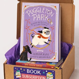 Puede incluir: Una caja de suscripción de libros de cartón, llena de libros y papel de seda morado. El libro superior se titula "Puggleton Park" con una ilustración de un pug. La caja tiene una etiqueta que dice "Book Subscription Box".