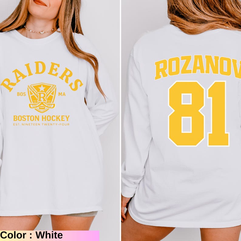 May include: White long-sleeve sweatshirt featuring "RAIDERS" and "BOSTON HOCKEY" text with a logo on the front. The back displays "ROZANOV 81" in yellow. The sweatshirt is a casual style, perfect for sports fans.
