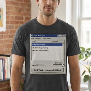 May include: Dark gray t-shirt featuring a graphic of a vintage computer Task Manager window. The window displays the text "Responsibilities" and "End Task: responsibilities". The shirt is a crew neck and is being worn.