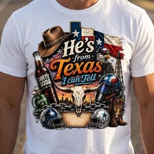 Puede incluir: Una camiseta blanca con un estampado gráfico que muestra un sombrero de vaquero marrón, una botella etiquetada como Dirty Soda, un cráneo de toro, una careta de soldar, dos cascos de fútbol americano y botas. El texto dice He's from Texas I can Tell.