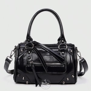 May include: A black handbag with a top handle and a detachable shoulder strap. The bag has a front zip pocket, decorative studs, and silver-tone hardware. The text "Black Lace" is visible on the bottom right.