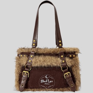 Op de afbeelding: Een bruine en tan faux fur handtas met bruine leren riemen en goudkleurige hardware. De tas heeft een rechthoekige vorm met een klepsluiting en een logo met de tekst "Black Lace Nikkei".