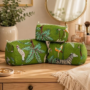 May include: Three rectangular quilted pouches in a vibrant green fabric featuring a repeating pattern of tropical birds, palm leaves, and a zebra. Each pouch has a striped trim along the top edge and a soft, stitched texture throughout the exterior.
