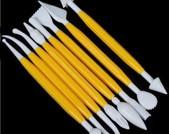 May include: Set of 7 yellow and white plastic fondant tools for cake decorating. The tools have different shapes for creating various designs.
