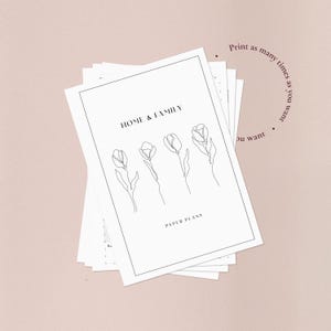 Puede incluir: Una pila de planes en papel blanco con el texto "HOME & FAMILY" y "PAPER PLANS" en un dise&ntilde;o minimalista. La portada presenta un dibujo lineal de cuatro tulipanes. Tambi&eacute;n es visible el texto "Imprime tantas veces como quieras".