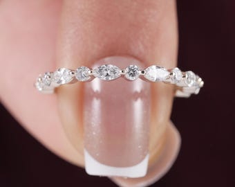 May include: A silver-toned band ring featuring an alternating pattern of marquise-cut and round-cut clear stones. The stones are set in a continuous row along the metal band, creating a sparkling, symmetrical design across the entire visible length.