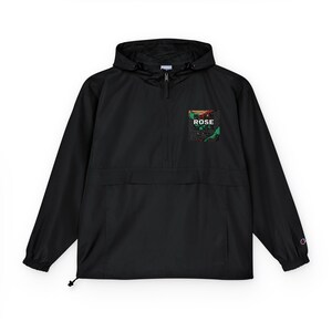 Puede incluir: Chaqueta anorak negra con capucha y cierre de media cremallera. La chaqueta presenta un pequeño parche cuadrado en el pecho con la palabra "ROSE" y un diseño colorido. El logo de Champion es visible en la manga.