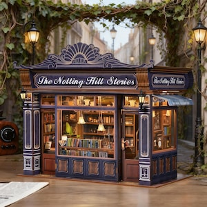 May include: A miniature model of "The Notting Hill Stories" bookstore. The facade is a deep blue with gold accents, featuring a detailed sign and small lamps. The interior is visible, filled with tiny books and warm lighting, creating a cozy, inviting scene.