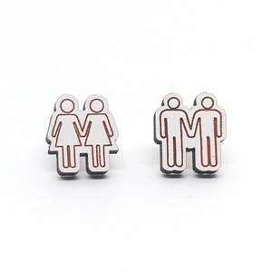 May include: Two pairs of wooden earrings, one pair features two women holding hands and the other pair features two men holding hands.