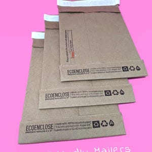 May include: Three brown padded mailers with white tape seals. The mailers are stacked on top of each other. The mailers are made with 100% recycled paper and printed with algae ink. The mailers are 6 x 9 inches. The text "ECOENCLOSE" and "PADDED MAILER 6 x 9" is printed on the mailers. The text "Eco Friendly Mailers" is printed below the mailers.