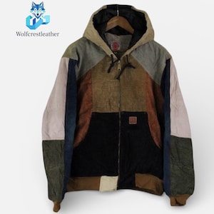 May include: A multi-coloured corduroy jacket with a hood. The jacket features a patchwork design with panels of olive green, brown, black, and beige. It has a full-length zip and a small square patch on the front pocket. The brand name "Wolfcrestleather" is visible.
