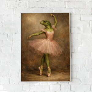 May include: A framed art print depicts a green lizard-like creature in a pink tutu and ballet shoes, striking a graceful pose. The artwork has a vintage aesthetic with a soft, brown background, and is mounted on a white brick wall.