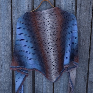 May include: A triangular knitted shawl featuring a gradient color transition from light blue to deep brown and beige. The accessory displays a delicate openwork lace pattern throughout the center, complemented by horizontal textured stripes.