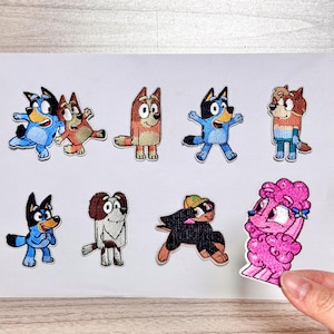 Può includere: Una collezione di toppe ricamate con personaggi di cani dei cartoni animati in varie pose e colori. Le toppe includono cani blu, marroni e rosa con diverse espressioni e abiti. Ideali per decorare abbigliamento o accessori.