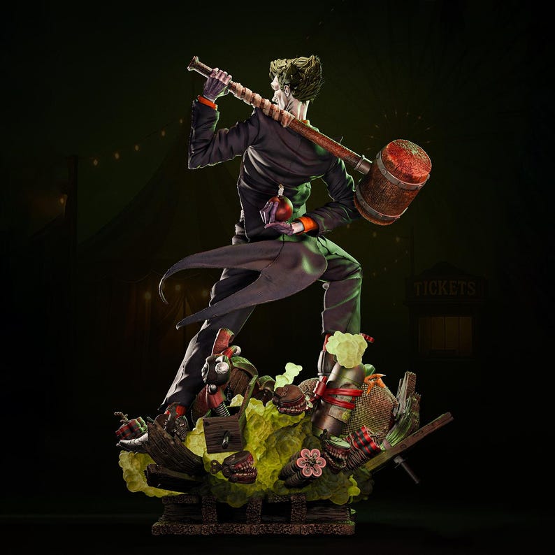 May include: A detailed statue of the Joker, a DC Comics character, holding a large mallet over his shoulder. He wears a black suit with orange accents and stands on a chaotic base with various props. The statue has a dark, theatrical aesthetic.