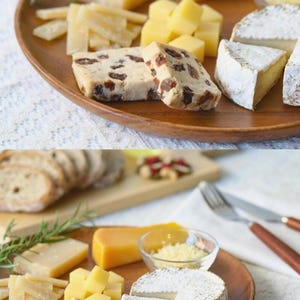 Pode incluir: Uma tábua de madeira com uma variedade de queijos, incluindo brie, cheddar e um queijo com passas. Os queijos são dispostos com raminhos de alecrim e pequenas tigelas de queijo ralado.