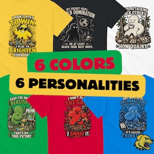May include: Six t-shirts in yellow, black, white, green, red, and blue, each featuring a unique board game character graphic with text. The designs include phrases like I DON'T PLAY TO WIN, MY SECRET GOAL, and I SMASH IT, showcasing various game-themed art.