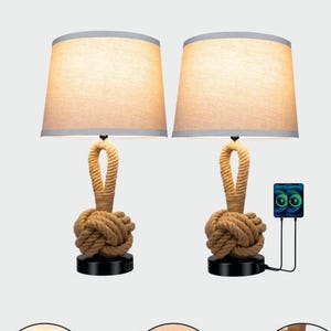 May include: Two beige lamps with rope knot bases and beige fabric shades. The lamps have a gray trim on the top and a black base. One lamp has a USB charging port. The lamps are on a light gray background.