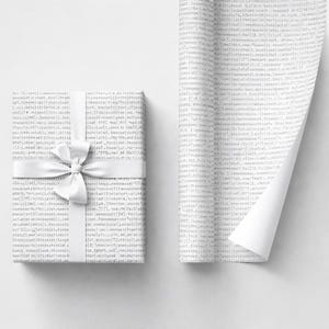 May include: A wrapped gift with white paper printed with lines of code, tied with a white satin bow. The gift is on a white background, with a partially unrolled sheet of the same code-printed paper.