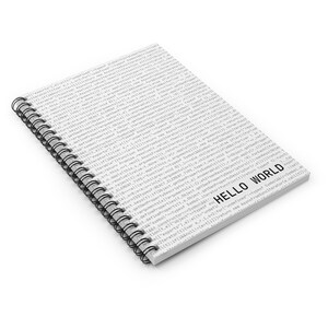 Angled view of white developer notebook featuring code-style background and ‘Hello World’ typography.