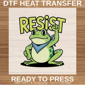 Puede incluir: Un diseño de transferencia de calor DTF con una rana de dibujos animados que lleva un pañuelo azul, levantando una mano y la palabra "RESIST" en letras verdes. La rana es verde con manchas verdes oscuras. El texto "READY TO PRESS" está en la parte inferior.
