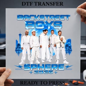 May include: A DTF transfer sheet featuring the text BACKSTREET BOYS SPHERE 2026 in a metallic blue font. The design includes a group of five individuals dressed in white outfits standing before a blue glowing sphere and a city skyline silhouette.