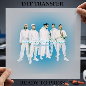 May include: A DTF transfer sheet featuring a graphic of the Backstreet Boys in white outfits against a blue gradient background. The text reads DTF TRANSFER at the top, INTO THE MILLENNIUM in the centre, and READY TO PRESS at the bottom.