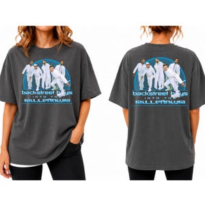 Könnte beinhalten: Ein anthrazitfarbenes T-Shirt mit einer Grafik der Backstreet Boys in weißen Outfits vor einer blauen Gitterkugel. Der Text lautet Backstreet Boys Into The Millennium in einer stilisierten blauen Schrift. Das Motiv ist vorne und hinten gedruckt.