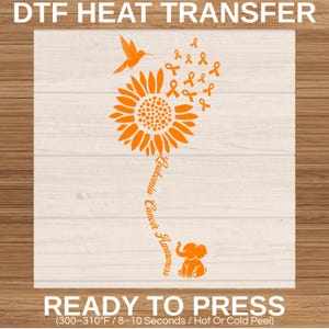 May include: An orange DTF heat transfer featuring a sunflower with a hummingbird, multiple awareness ribbons, and an elephant. The stem contains the text Leukemia Cancer Awareness. The design includes instructions for 300-310°F and 8-10 seconds.