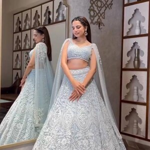 May include: A light blue, embroidered lehenga set with a matching crop top and cape. The lehenga features intricate floral patterns. The text "MUST try this DUPATTA HACK" is visible in the background.