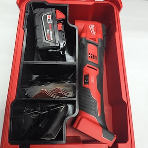 May include: A red tool case with a clear lid, housing a red and black oscillating multi-tool, a black battery, and other accessories. The case is sectioned for tool and accessory storage.
