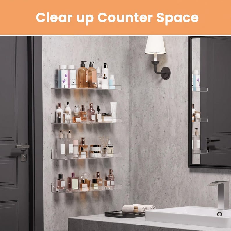 May include: Four clear acrylic wall-mounted shelves arranged vertically, holding various skincare and cosmetic bottles. The text "Clear up Counter Space" appears at the top. The shelves are installed on a light gray wall next to a bathroom mirror.