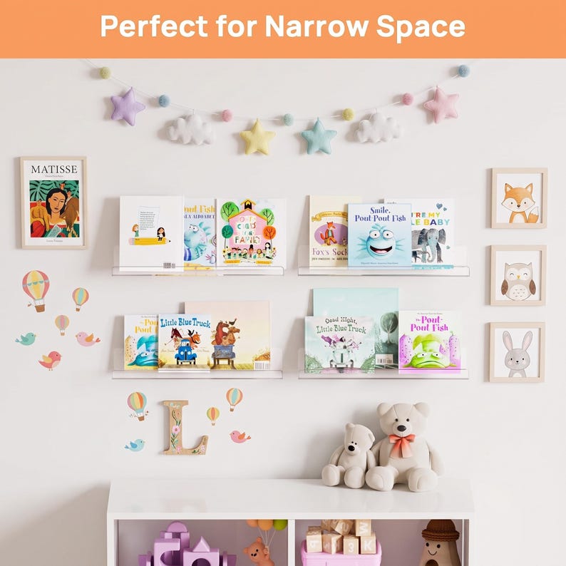 May include: Four clear acrylic floating wall shelves holding children's books, arranged in two rows. The wall features a star and cloud garland, framed art prints of a person, fox, owl, and rabbit, plus hot air balloon and bird wall decals.