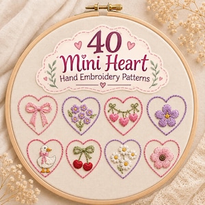 Può includere: Un telaio da ricamo in legno contenente tessuto color bianco sporco con il testo 40 Mini Heart Hand Embroidery Patterns. Sotto il testo ci sono otto disegni di cuori ricamati con un fiocco rosa, fiori viola, cuori pendenti, un fiore, un'anatra, ciliegie, margherite e un fiore rosa.