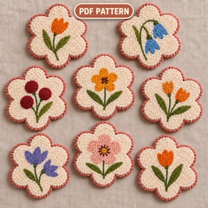 Könnte beinhalten: Acht blumenförmige Punch-Needle-Untersetzer mit cremefarbenen Zentren und rosafarbenen Rändern. Jedes Stück zeigt ein einzigartiges gesticktes Blumenmotiv, darunter Tulpen, Beeren und verschiedene Blüten. Ein Etikett oben zeigt PDF PATTERN.