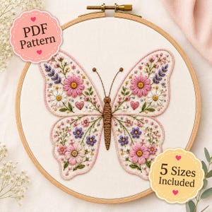 Könnte beinhalten: Ein Stickrahmen mit einem Stoffeinsatz, der ein Schmetterlingsmotiv zeigt. Der Schmetterling hat einen braunen Körper und Flügel, die mit rosa, weißen und violetten Blumenstickereien sowie kleinen Herzen verziert sind. Text: PDF Pattern und 5 Sizes Included.