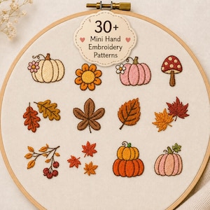 Könnte beinhalten: Ein hölzerner Stickrahmen mit cremefarbenem Stoff, der verschiedene gestickte Herbstmotive wie Kürbisse, Pilze, Blätter und Beeren zeigt. Ein gewelltes Etikett am oberen Rand trägt die Aufschrift 30+ Mini Hand Embroidery Patterns.