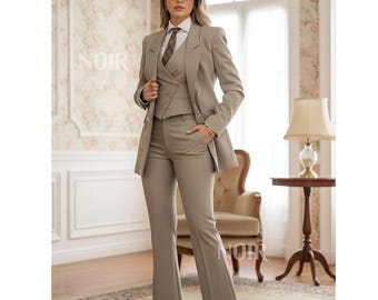 May include: A three-piece taupe suit with a blazer, vest, and flared trousers. The suit includes a white collared shirt and a patterned tie. The word "NOIR" is visible on the wall. The suit is worn with sunglasses.