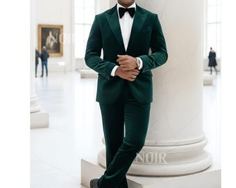May include: A dark green velvet suit with a black bow tie and a white dress shirt. The suit is worn with black dress shoes and a silver watch. The person is standing in a museum setting.