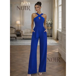 May include: A cobalt blue jumpsuit with a halter neckline and wide-leg pants. The jumpsuit features a criss-cross design at the chest and pockets. The word "NOIR" is printed at the top of the image.