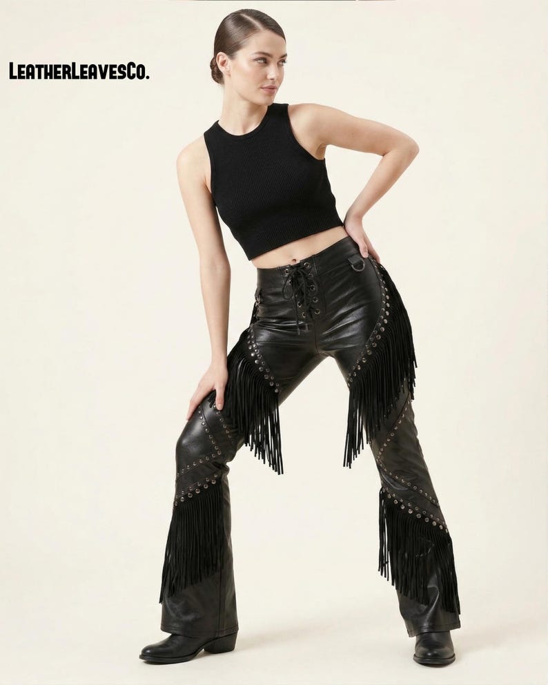 May include: Black leather trousers with fringe and stud detailing. The trousers feature a lace-up front and are worn with a black ribbed crop top. The text "LEATHERLEAVESCO." is visible in the upper left corner.