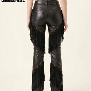 May include: Black leather trousers featuring fringe trim and stud embellishments. The design includes a five-pocket style and a straight leg cut. The text "LEATHERLEAVESCO." is displayed in the top left corner.
