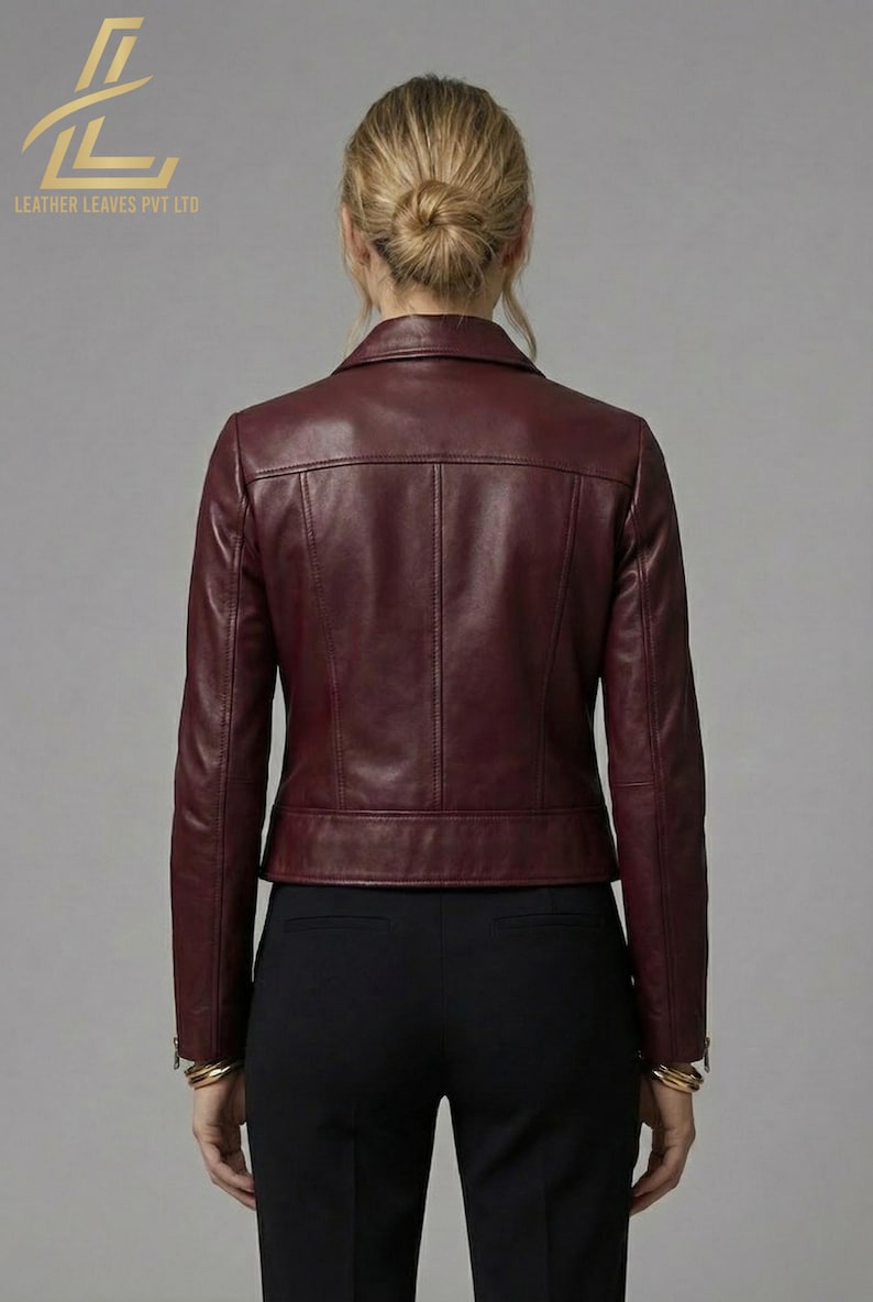 May include: Burgundy leather jacket with a classic collar and a tailored fit. The jacket features a front zipper closure and a subtle, textured finish. The back view showcases the jacket's design and stitching details. The brand logo is visible in the upper left corner.