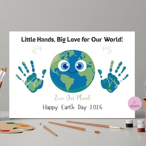 May include: A white canvas print with the text "Little Hands, Big Love for Our World!" and "Happy Earth Day 2026." The artwork features a smiling Earth and handprint designs in shades of blue and green. A cactus in a terracotta pot is on the right.