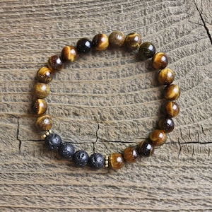 May include: A brown and gold tiger's eye beaded bracelet with black lava rock beads.