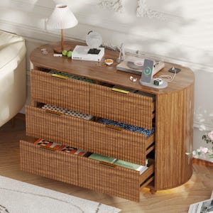 May include: A wooden, oval-shaped cabinet with three drawers, each partially open. The cabinet has a textured, vertical-lined design. The top surface holds a lamp, books, a globe, and a record player. The drawers reveal colorful contents.