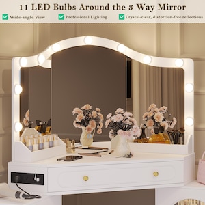 May include: A white vanity with a three-way mirror, illuminated by 11 LED bulbs. The vanity features drawers with gold knobs and is adorned with floral arrangements and beauty products. Text on the image reads: "11 LED Bulbs Around the 3 Way Mirror."