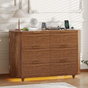 May include: A wooden dresser with six drawers and gold-colored handles. The dresser has a textured front and sits on short, decorative legs. A lamp, globe, and other items are on top.